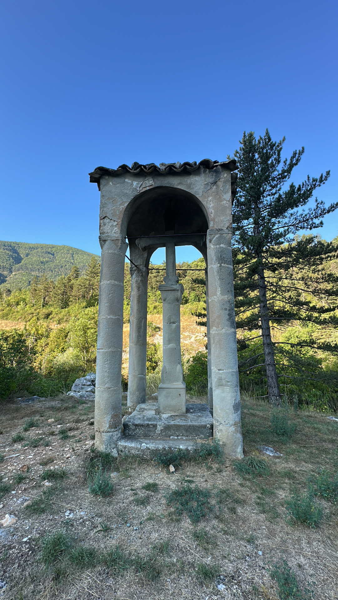 La Croix romane d'Annot sous son baldaquin de quatre colonnes couvert de tuiles, dans la campagne