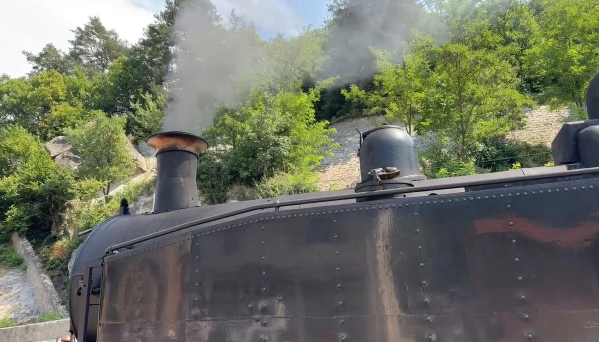 La cheminée de la locomotive à vapeur crachant sa fumée au départ