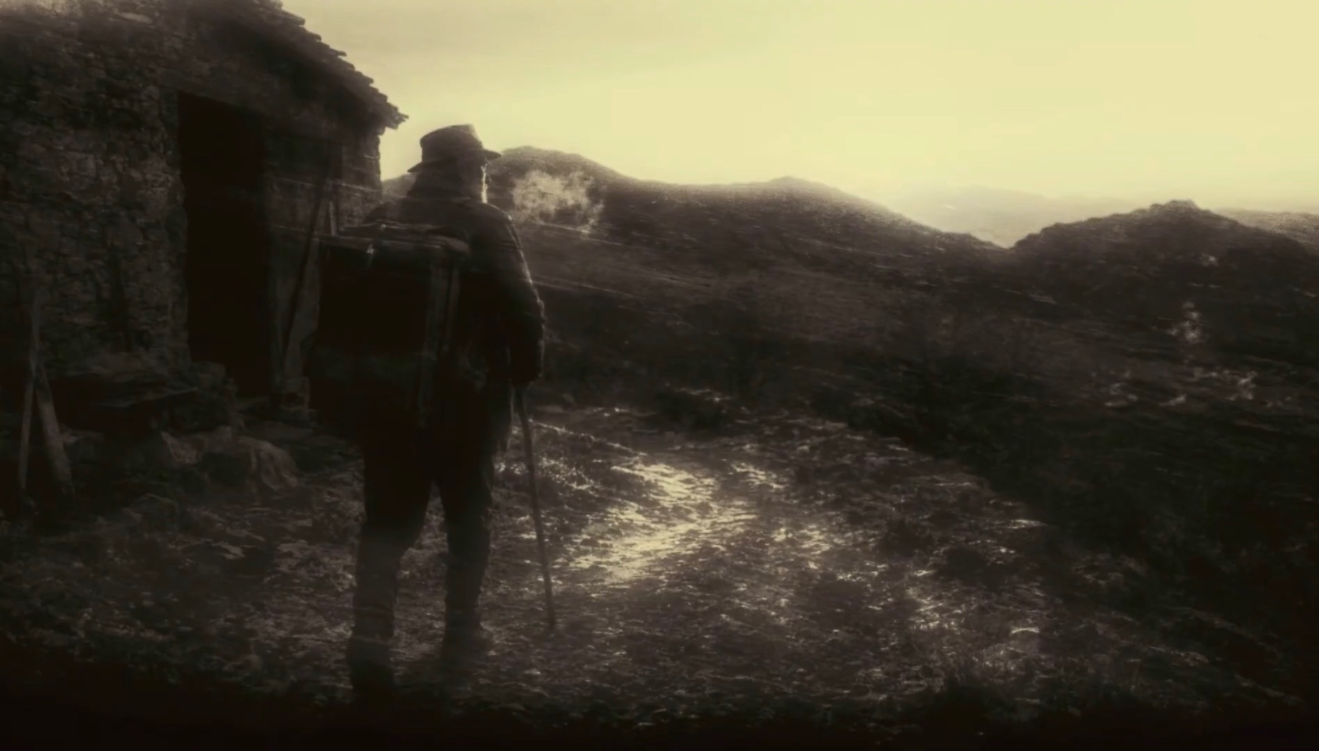 Photogramme du film : un colporteur marchant sur un chemin de montagne au petit matin